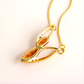 Gold amber necklace with a leaf-shaped pendant on a light pink background