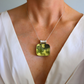amber Necklace with a green pendant worn by a person in a white top