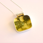green amber necklace on a light pink background