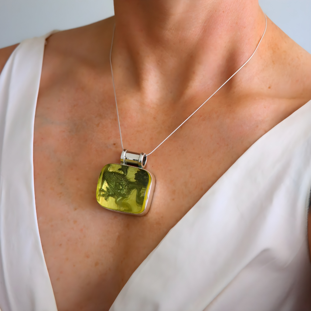 amber Necklace with a green pendant worn by a person in a white top