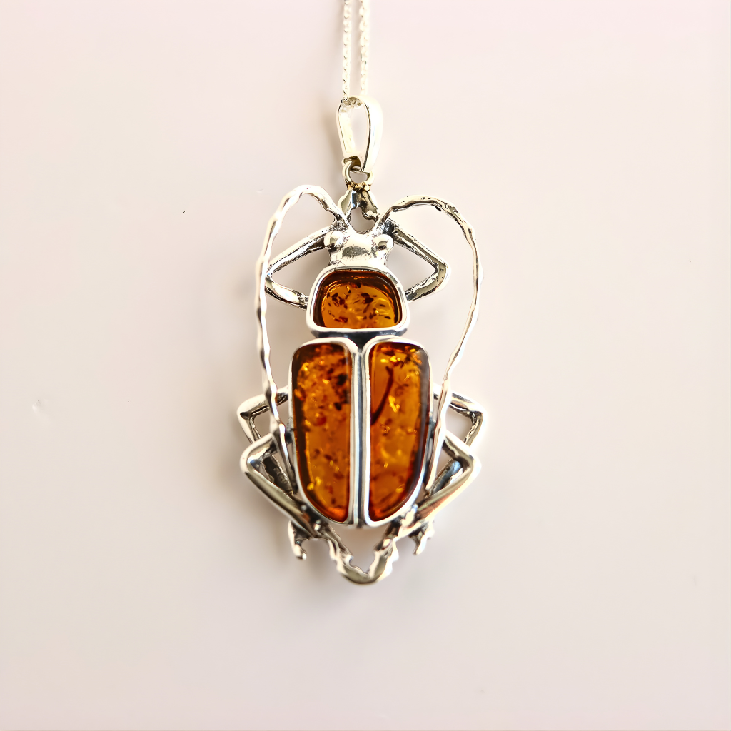 Silver scarab pendant with amber-colored stone on a light background