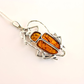 Silver scarab pendant with amber stones on a white background