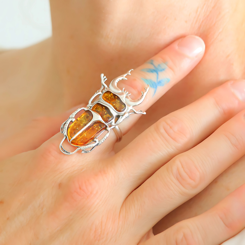 Silver scarab ring with amber stones on a finger