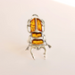 Silver scarab ring with amber stones on a light background