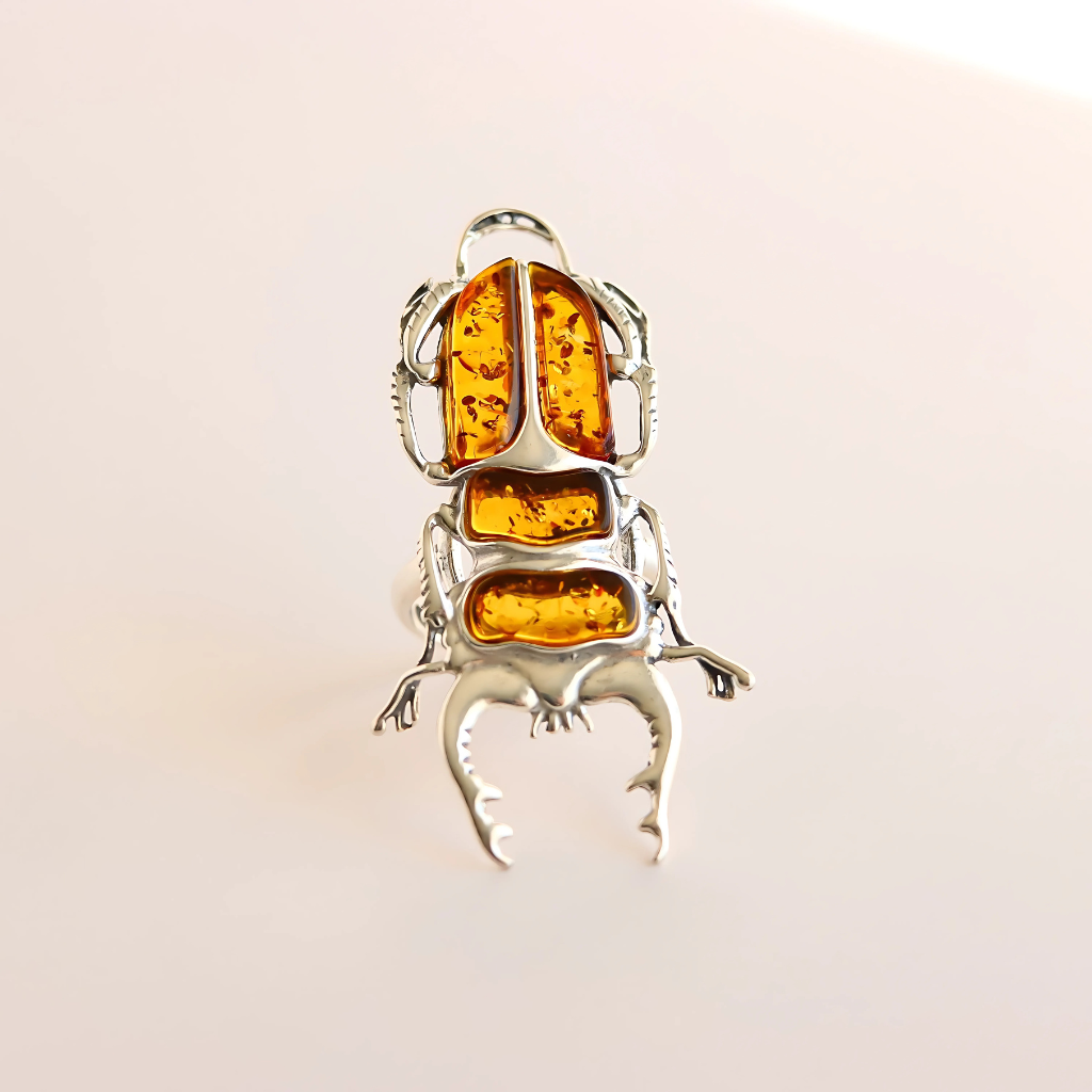 Silver scarab ring with amber stones on a light background