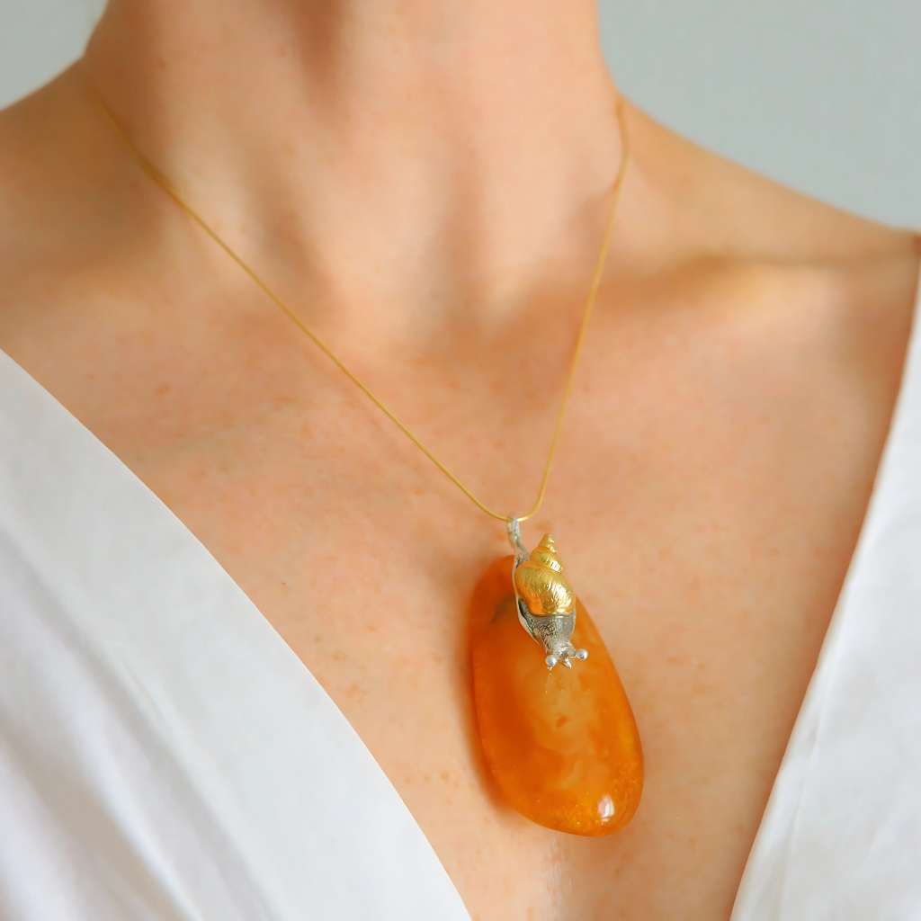 statement Necklace with an orange pendant on a person wearing a white top.