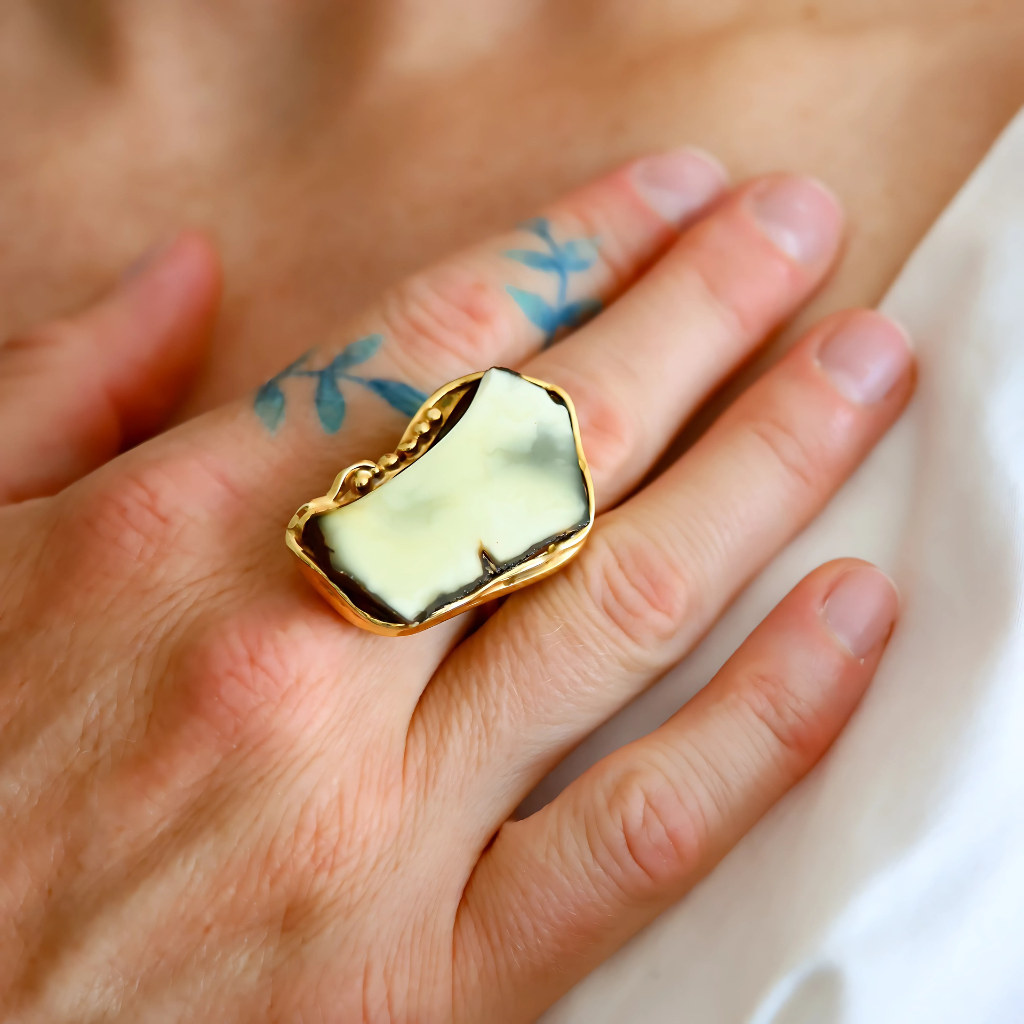 Front view of Baltic amber statement ring with white and black amber in gold plated sterling silver setting