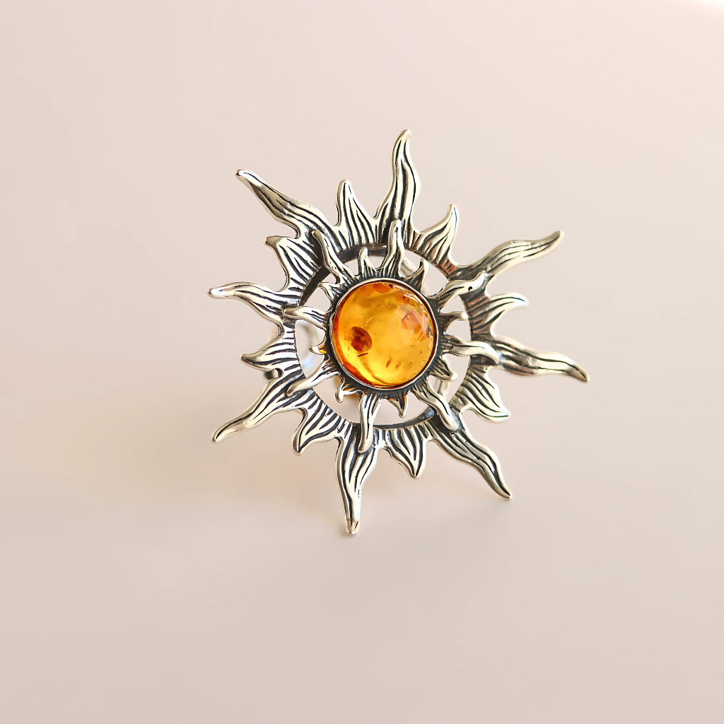 Silver sun ring with a orange gemstone on a beige background