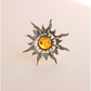 Silver sun ring  with a central amber gemstone on a beige background