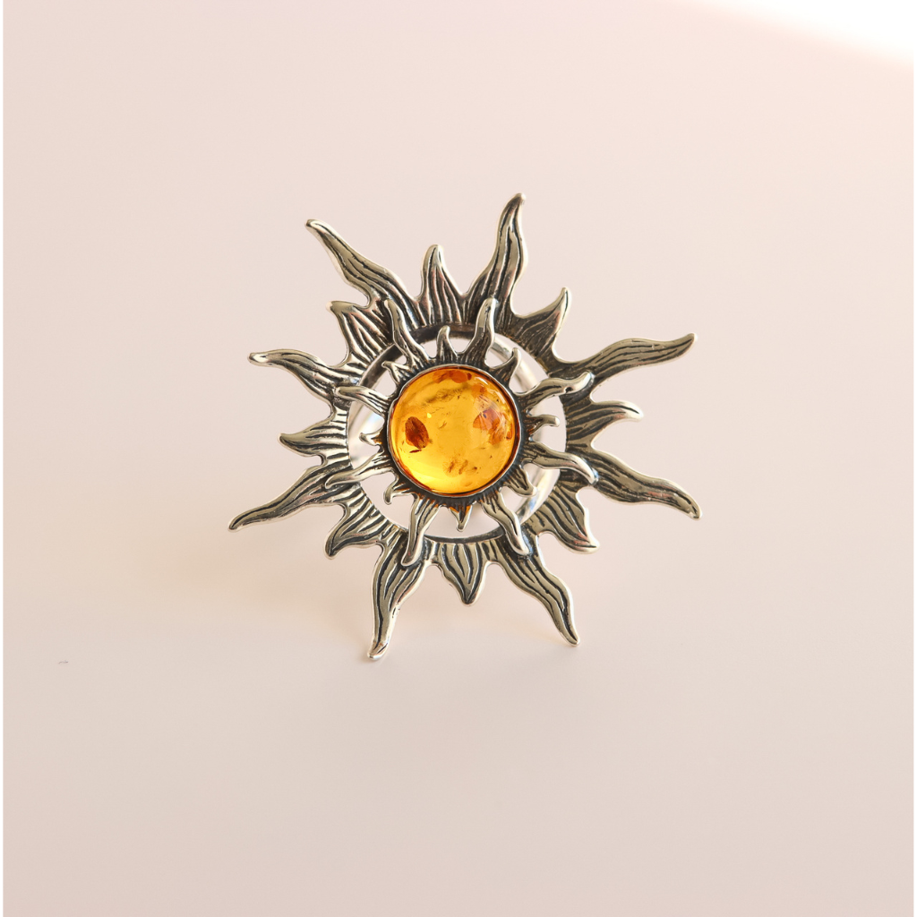 Silver sun ring  with a central amber gemstone on a beige background