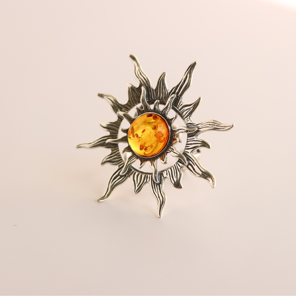 Silver sun ring with a amber stone on a beige background