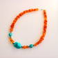 beaded Necklace with orange beads and turquoise stones on a light background