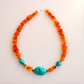 beaded Necklace with orange beads and turquoise stones on a light background
