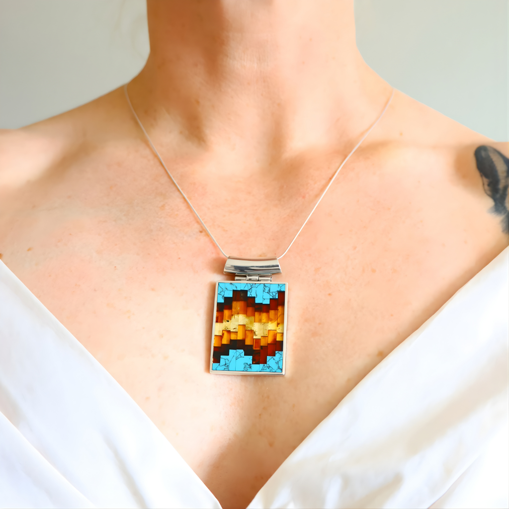turquoise Necklace with a colorful pendant on a person wearing a white top.