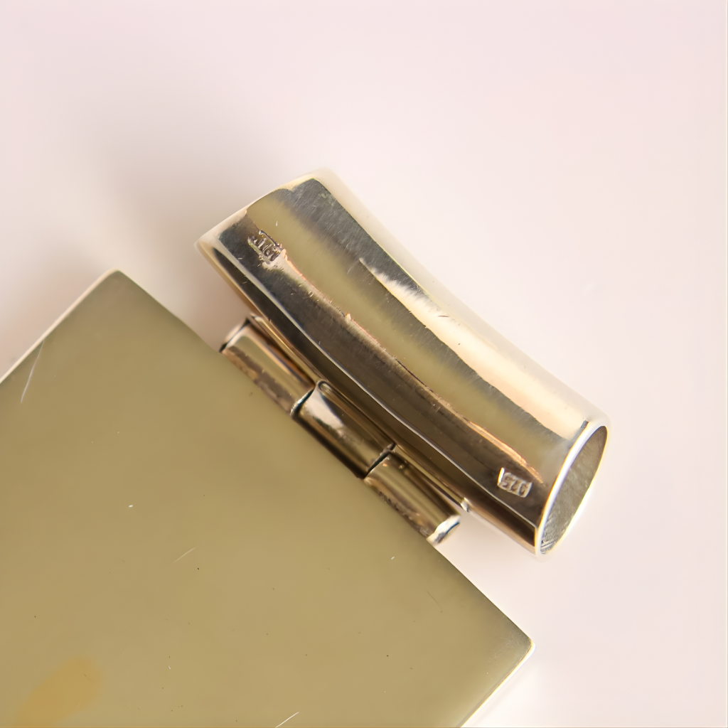 Close-up of a silver metallic hinge bail on a beige surface with a light background