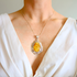Person wearing a butterscotch amber pendant necklace against a neutral background