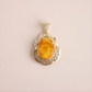 butterscotch amber pendant with a yellow stone on a beige background