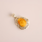 butterscotch amber pendant with a yellow stone on a beige background