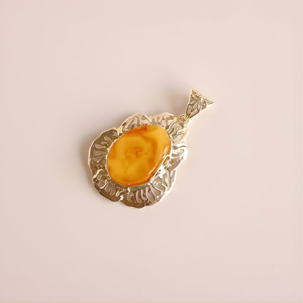 butterscotch amber  pendant with a yellow stone on a light pink background
