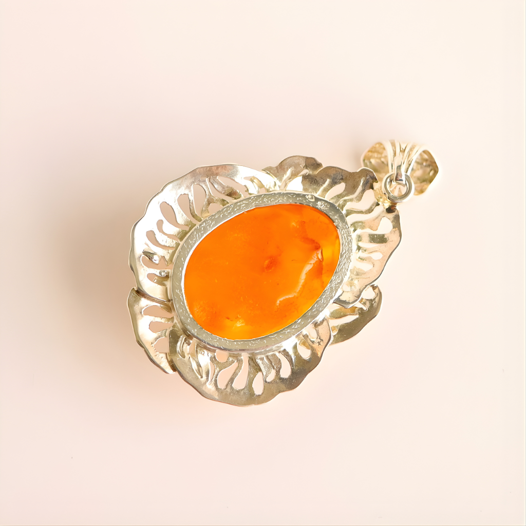 butterscotch amber pendant with an orange stone on a beige background