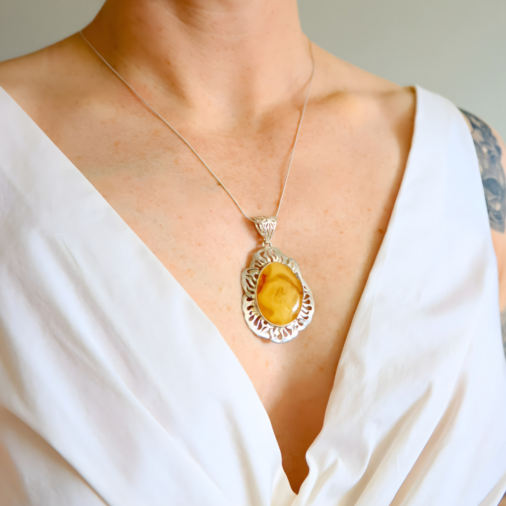 butterscotch amber pendant necklace on a person wearing a white top