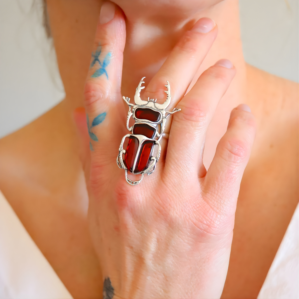 Silver amber ring with red stone on a person's finger