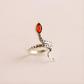 Silver snake ring with a red stone on a beige background