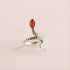 Silver snake ring with a red stone on a beige background