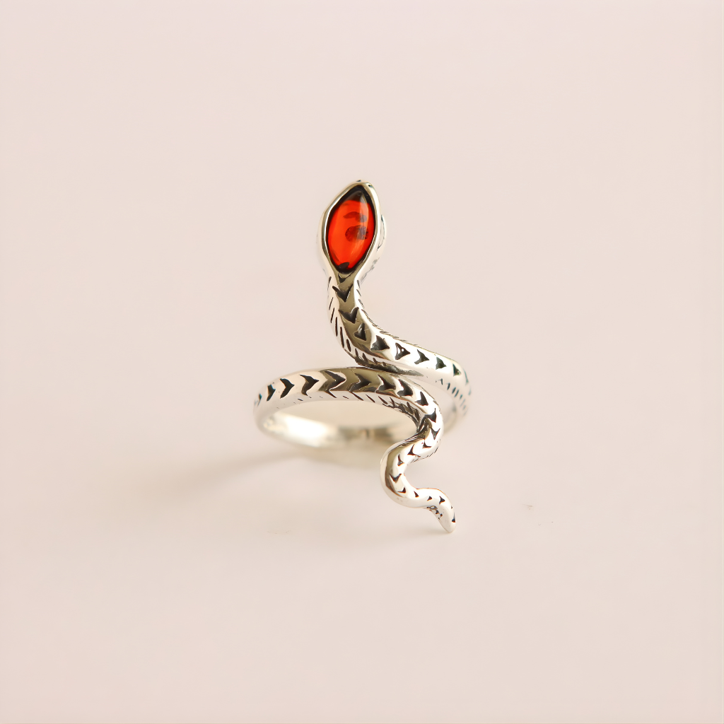 Silver snake-shaped ring with a red stone on a beige background