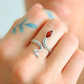 Silver snake-shaped ring with a red stone on a person's finger.