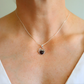 Silver spider charm necklace with a heart-shaped pendant worn by a person