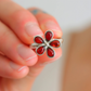 Silver ring with red gemstones held in a hand against a blurred background