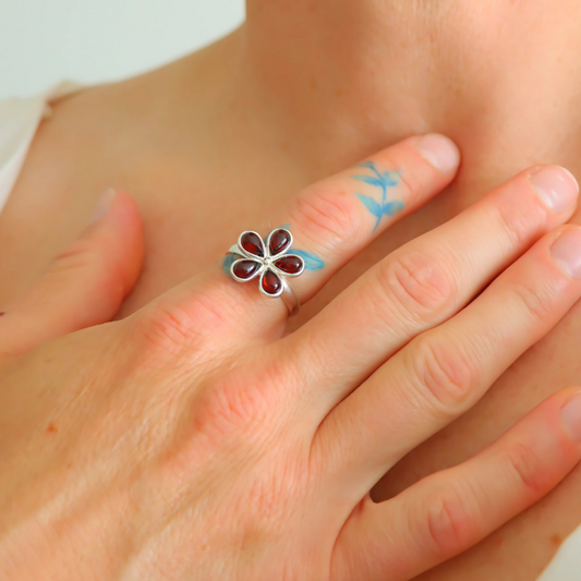 Silver amber ring with a floral design on a person's finger