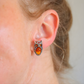 Close-up of an ear wearing silver amber owl earring with a blurred background