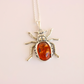 Silver amber pendant necklace with amber stone on a light pink background