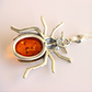 Spider-shaped amber pendant necklace with amber center on a light background