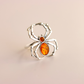 Silver spider amber ring with amber stones on a beige background