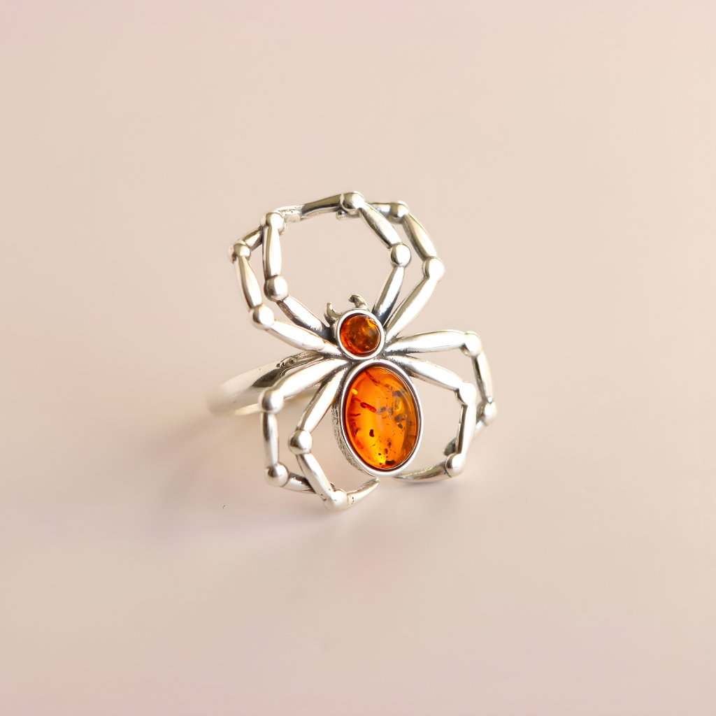 Silver spider amber ring with amber stones on a beige background