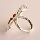 Silver amber ring with a spider design and amber stones on a light background
