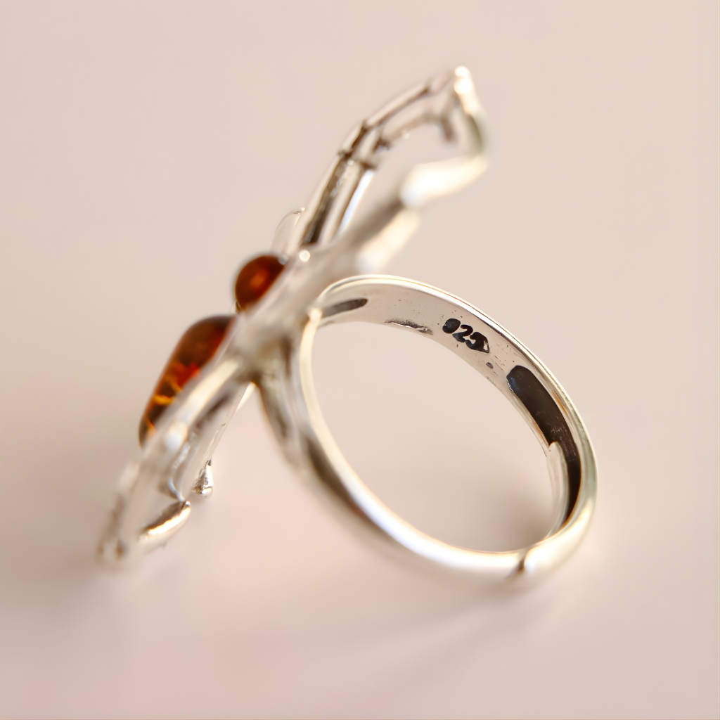 Silver amber ring with a spider design and amber stones on a light background