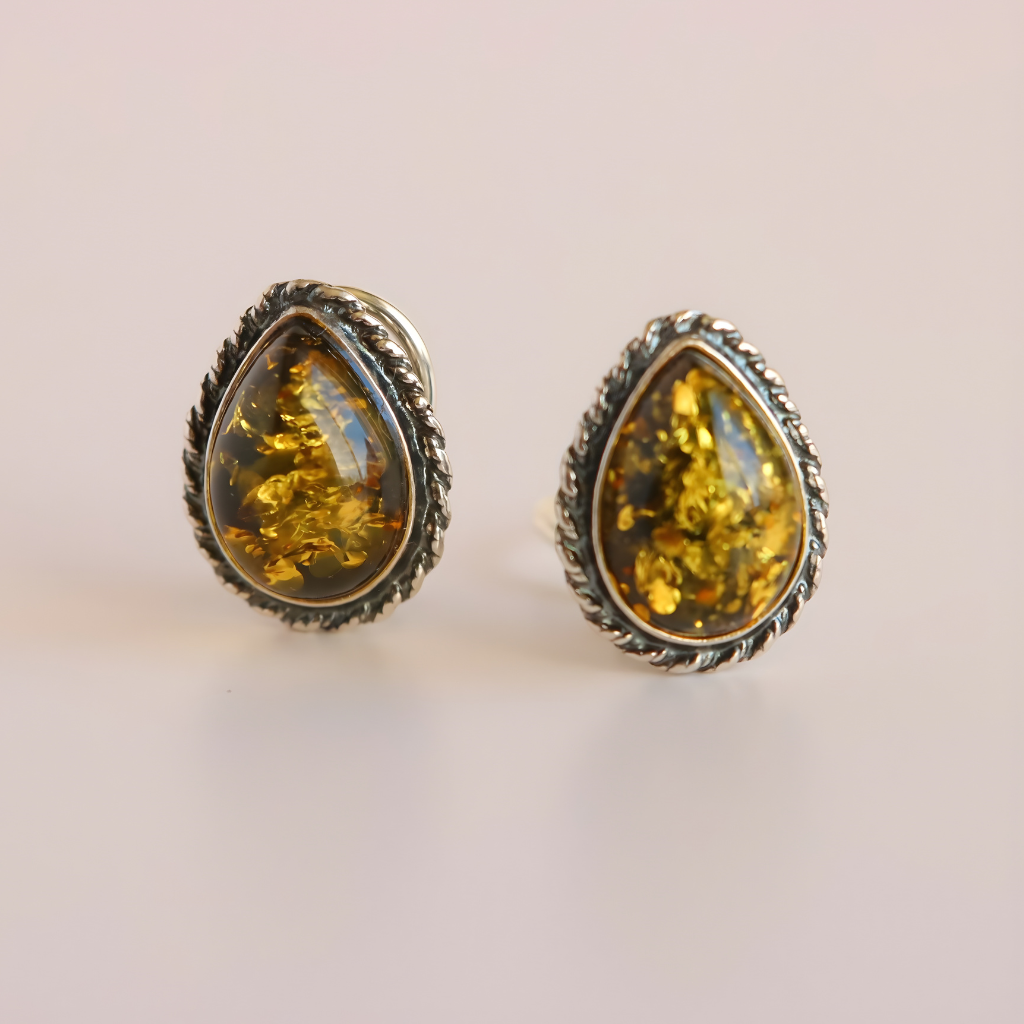 Pair of amber teardrop clip on earrings with silver settings on a light background