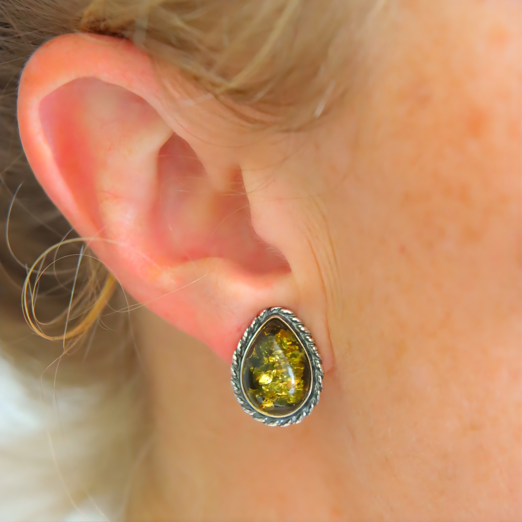 Close-up of an ear wearing a green teardrop clip on earring.