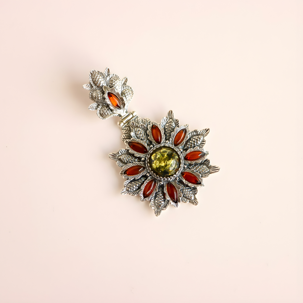 Decorative green amber floral pendant with silver accents on a beige background