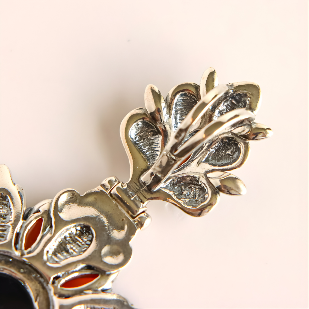 Close-up of a green amber floral pendant with intricate design on a light background