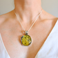 Green amber Necklace with a green amber pendant on a person wearing a white top.