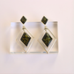 Pair of green amber earrings with geometric design on a white background