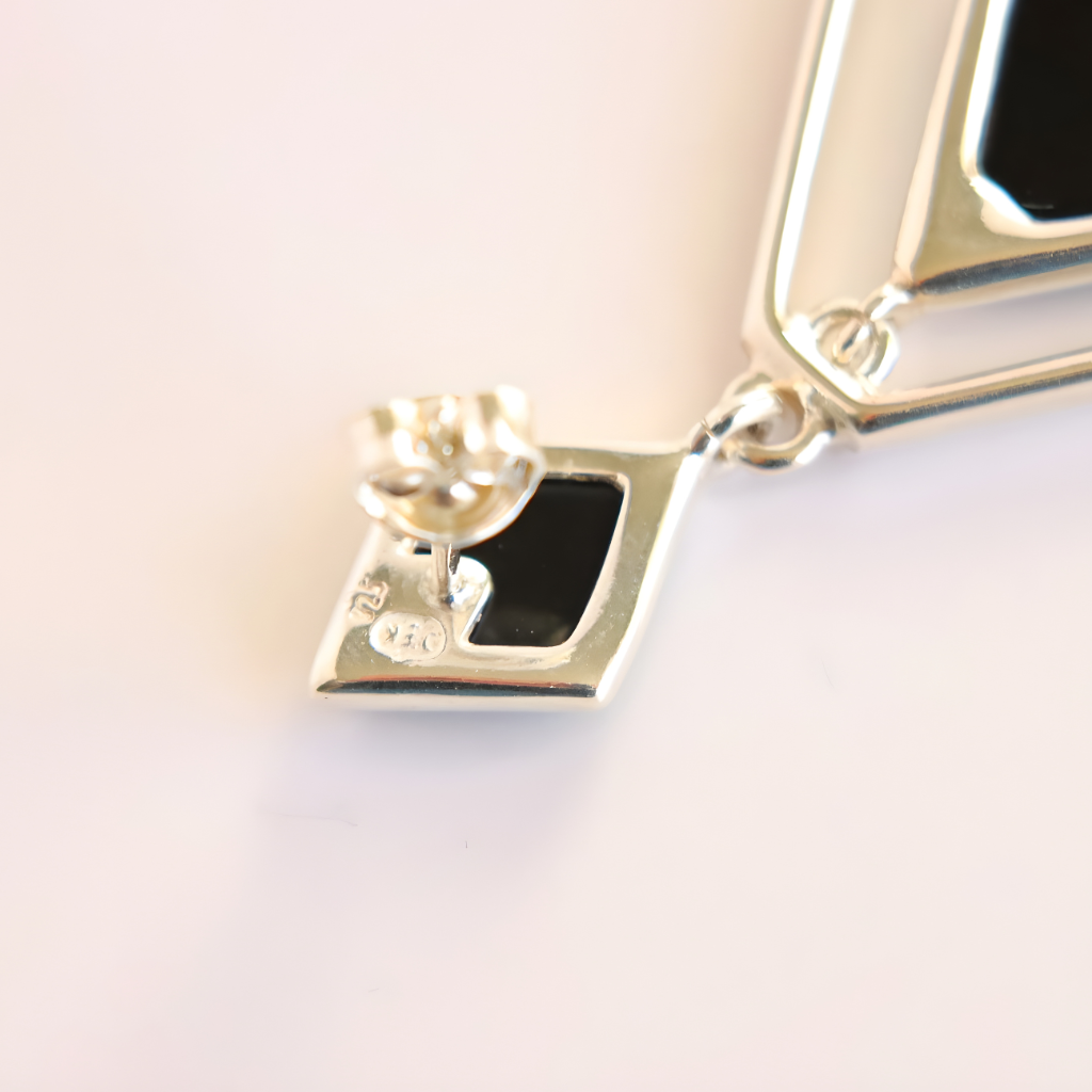 Close-up of a silver green amber earring with a clear gemstone on a light background