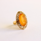 Gold amber ring with a yellow gemstone on a light background