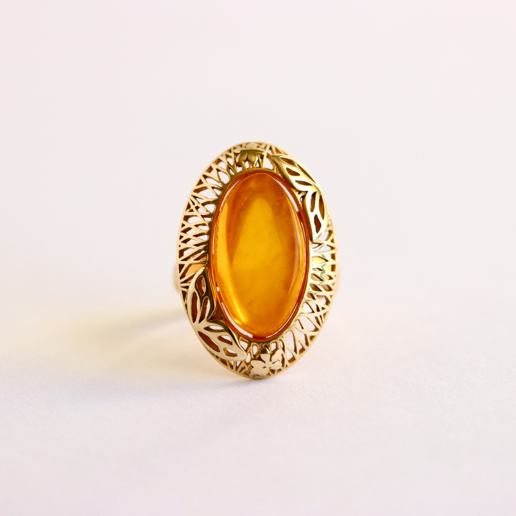 Gold amber ring with a yellow gemstone on a white background