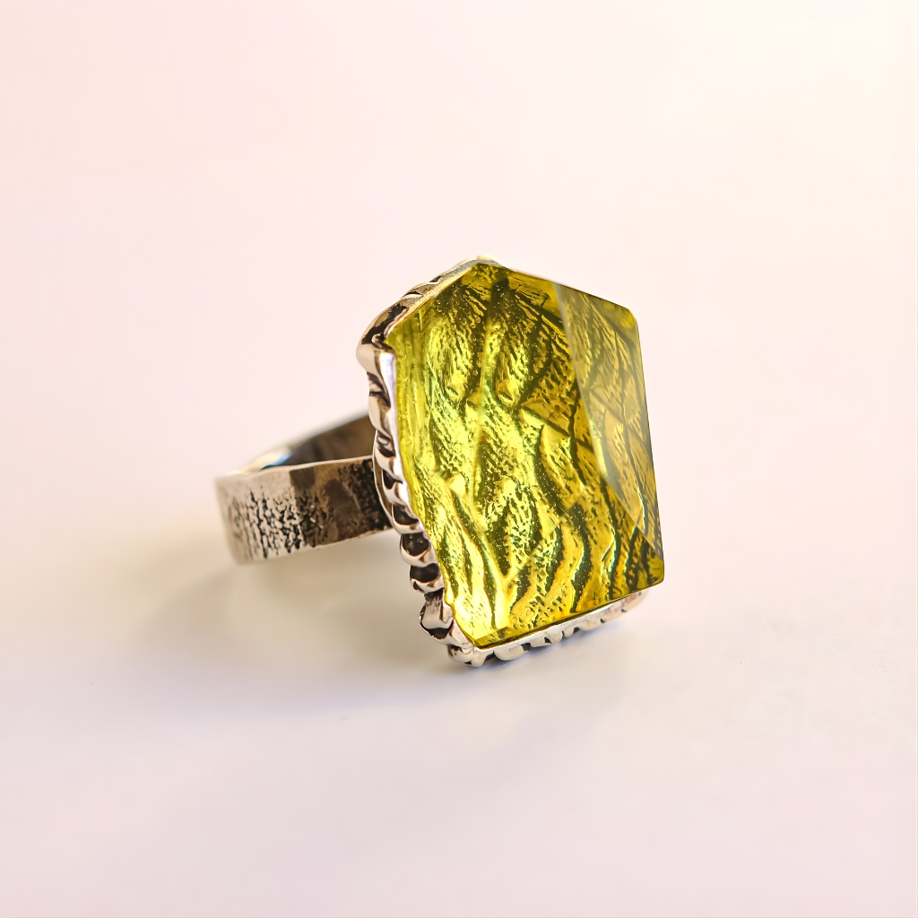 amber Ring with a green gemstone on a light pink background